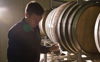 A man standing by wine barrels